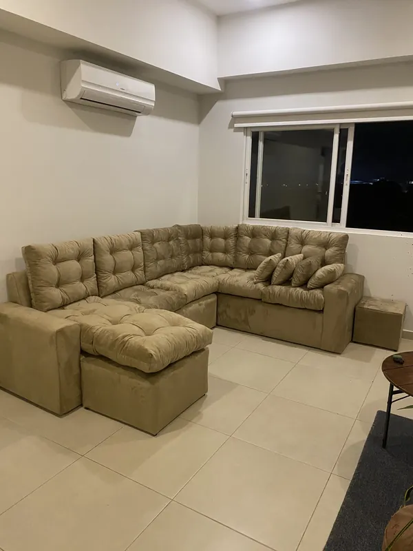 Sofá en U beige todo abotonado, con puff